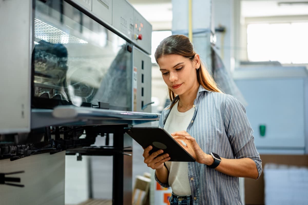 Technical professional reviewing work on a tablet in a workshop.
