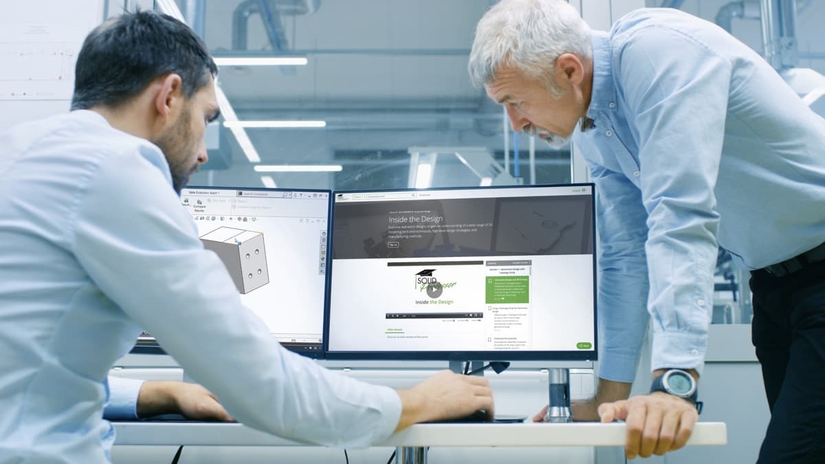 Two engineers reviewing a SolidProfessor course together at a workstation.