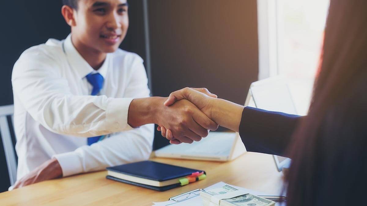 A mechanical engineer shaking hands with his hiring manager after salary negotiation