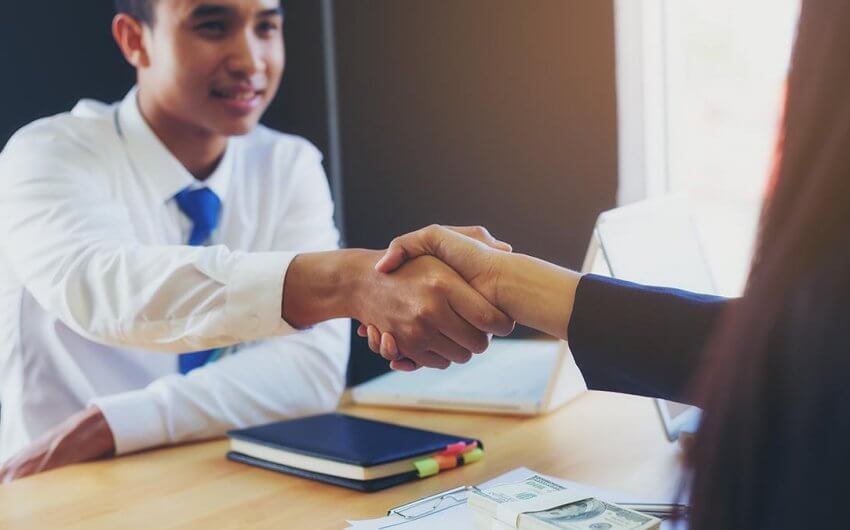A mechanical engineer shaking hands with his hiring manager after salary negotiation